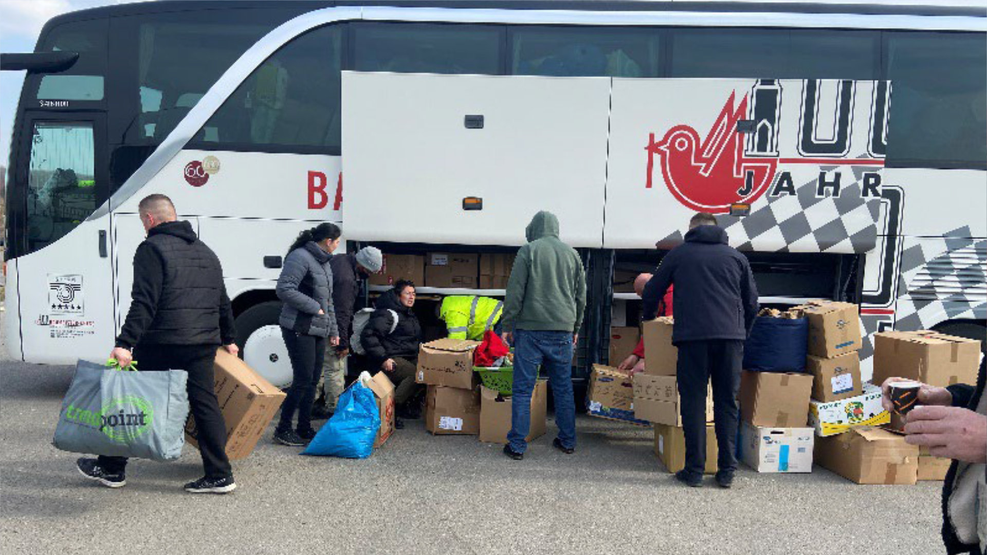 Freiwillige laden Hilfsgüter in einen Bus